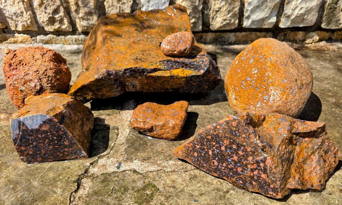 A group of llanite pieces, both river-tumbled and jewelry-grade rough.